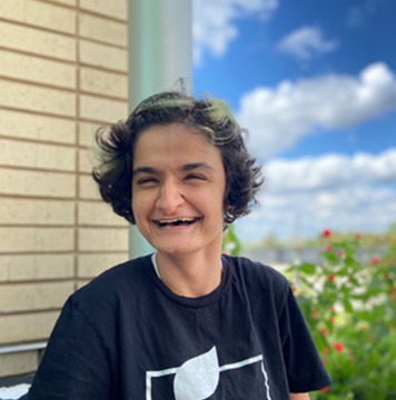 A woman with short black and green hair smiling at the camera